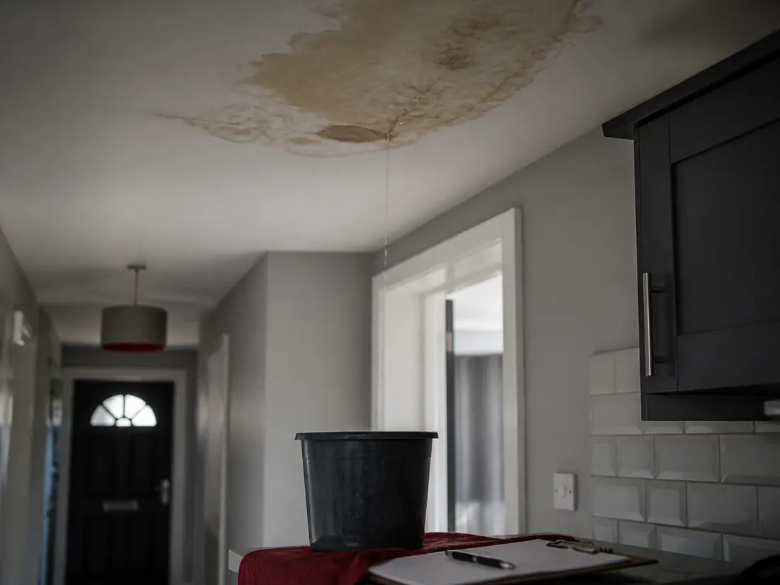 Water damage on a ceiling with a bucket below